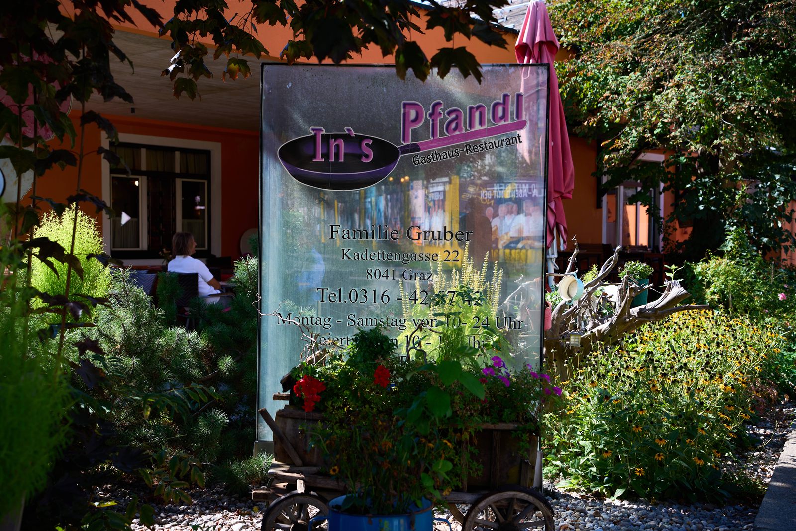 Eingangsschild des Gasthaus In's Pfandl mit Blumen